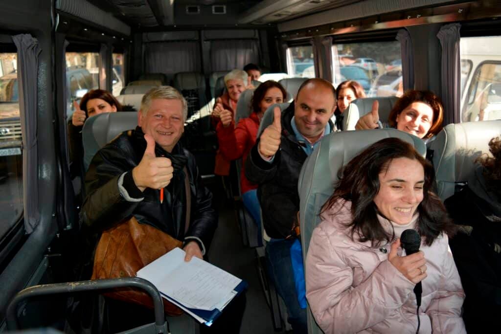 Course participants on a coach, practising guiding on a moving vehicle