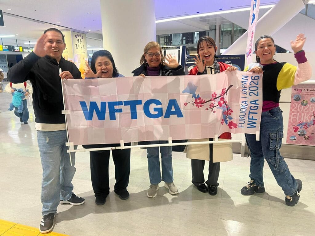 Tourist guides holding a WFTGA banner at the airport on their way to the 2026 Convention